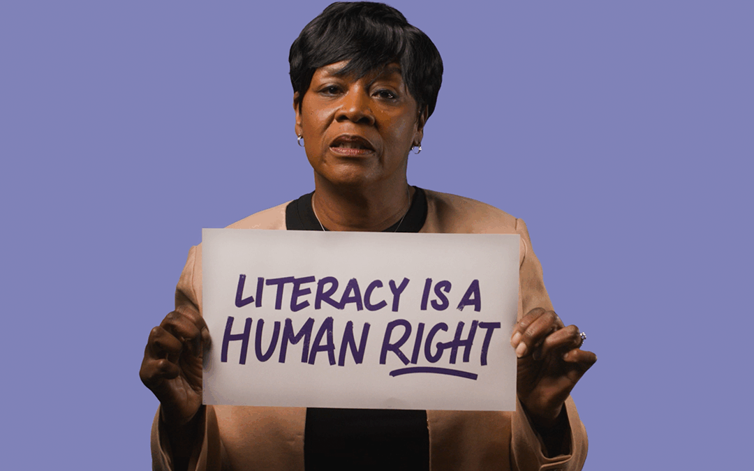 a woman holding up a sign reading "literacy is a human right"